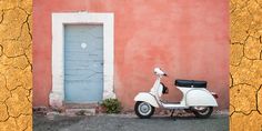 a white scooter parked in front of a pink wall with a blue door