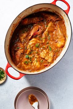 a pan filled with shrimp and sauce next to a bowl of green herbs on the side