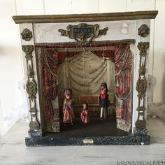 an ornate fireplace with two figurines on it's mantle and red curtains