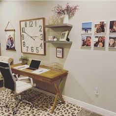 a desk with a laptop on it in front of a large clock and pictures hanging on the wall