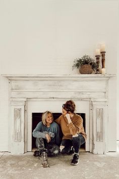 two women sitting on the floor in front of a fireplace