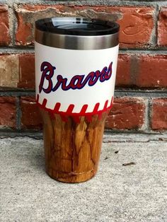 a wooden cup with the word braves painted on it sitting in front of a brick wall