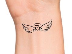 a small tattoo on the wrist with two hearts and an angel's wings in black ink