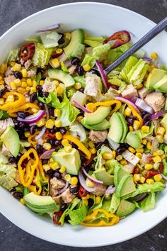 a salad with chicken, lettuce, black beans, corn and avocado