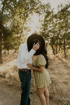 a man standing next to a woman wearing a cowboy hat