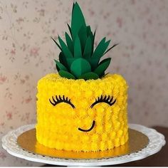 a yellow cake with a pineapple on top and eyes drawn on the side, sitting on a white plate