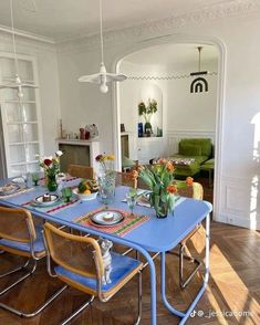 a dining room table set with place settings and flowers in vases on the table