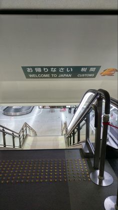 an escalator with metal handrails and signs above it