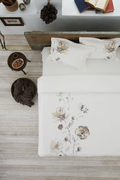 an overhead view of a bed with white sheets and flowers on it, along with other items