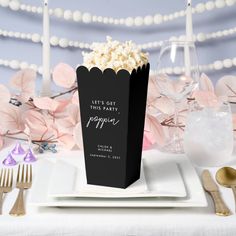 a black box filled with popcorn sitting on top of a table next to silverware