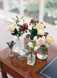 three vases filled with flowers sitting on top of a wooden table