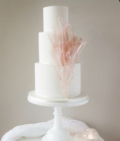 a three tiered white cake with pink flowers on top