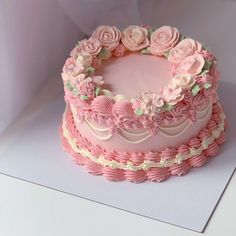 a pink cake decorated with flowers on top of a white tableclothed paper sheet