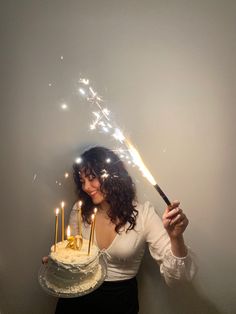 a woman holding a cake with sparklers on it