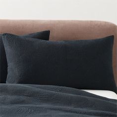 a bed with two black pillows on top of it