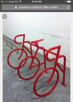 three red bicycle racks on the ground in a room with white walls and concrete flooring