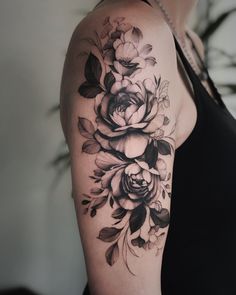 a woman with a black and white flower tattoo on her arm, showing off the shoulder