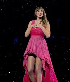 a woman in a pink dress standing on stage