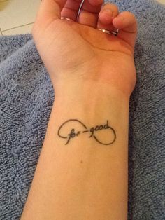 a woman's wrist tattoo with the word god and an infinite knot on it