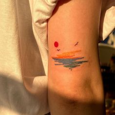 a person with a tattoo on their arm that has birds flying over the water at sunset