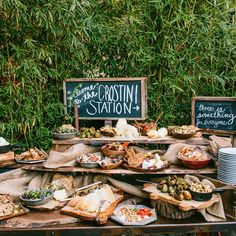 a table filled with lots of food sitting next to a sign that says crostini station