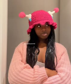 a woman wearing a pink knitted hat with horns on her head and arms crossed