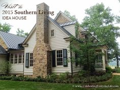 a white house with black shutters on the front and side windows, surrounded by greenery