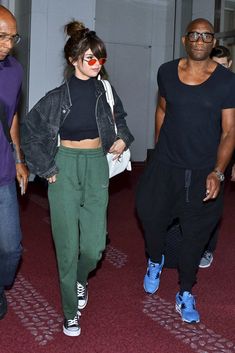 two people walking through an airport with one person wearing a clown nose and the other in green pants