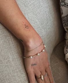 a woman's arm with tattoos and bracelets on her left wrist is shown