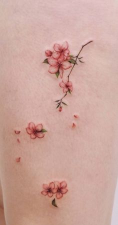 some pink flowers on the side of a woman's back, with small leaves