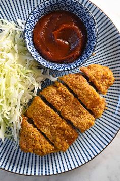 two pieces of fried chicken on a blue and white plate with coleslaw next to it