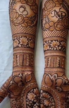 two hands with henna tattoos on them, one is showing the intricate design and the other has flowers