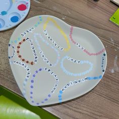 two heart shaped plates sitting on top of a wooden table next to paintbrushes