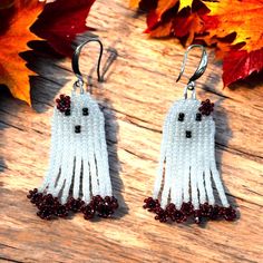 two pairs of white and red beaded tassels on wooden table next to autumn leaves