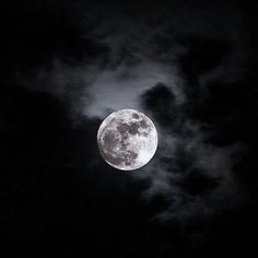 the full moon shines brightly in the dark night sky with some clouds behind it