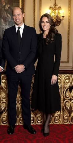 two men and a woman standing next to each other in front of an ornate wall