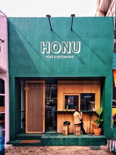 a man sitting at a table in front of a restaurant with green awnings