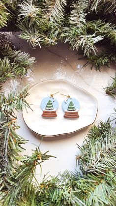 a pair of christmas tree earrings sitting on top of a plate