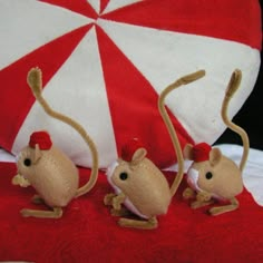 three stuffed mice sitting on top of a red and white pillow next to an umbrella