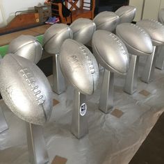 silver footballs are lined up on display in a room