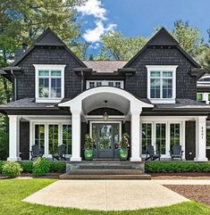 a large black and white house with lots of windows on the front door, and two story entryway