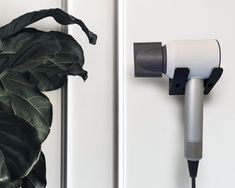 a hair dryer is plugged into the wall next to a potted plant