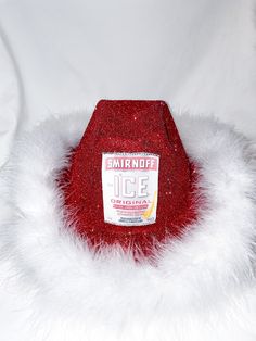 a red hat with white fur around it on top of a white surface and in the background is an ice cream container