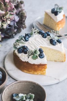 a piece of cake with white frosting and blueberries on top is sitting on a plate