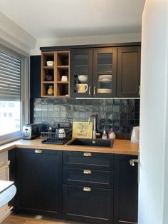 a kitchen with black cabinets and wooden counter tops