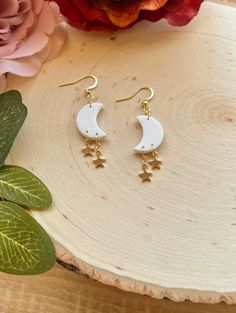 the moon and stars drop earrings are on display next to a bouquet of pink flowers