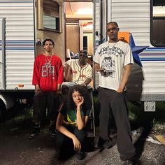 three men and a woman standing in front of a trailer