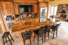 a large kitchen with an island and bar in the center, surrounded by black chairs