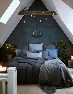 an attic bedroom decorated in grey and white with lights on the ceiling, bedding and pillows