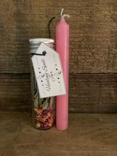 a pink candle sitting next to a jar filled with dried flowers